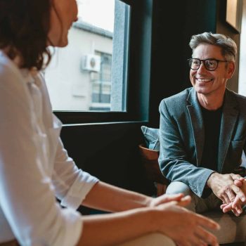 Two business people discussing in office lobby. Businessman talking with female colleague in office.