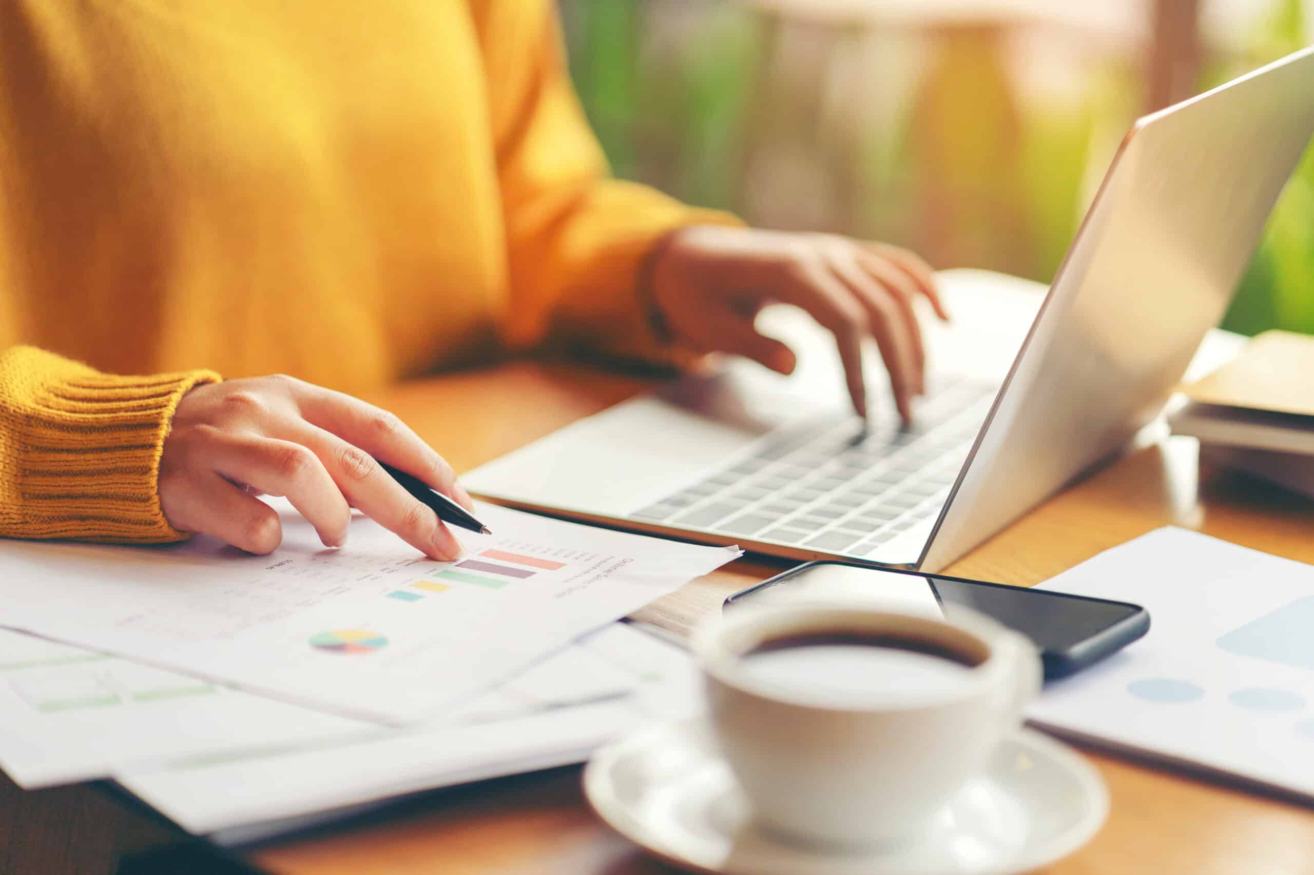 a woman checking documents while adding data to her PC